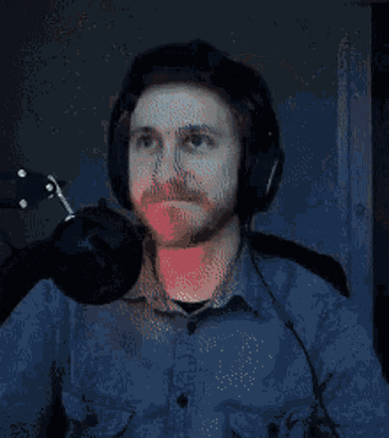 a man wearing headphones is sitting in front of a microphone and looking up .