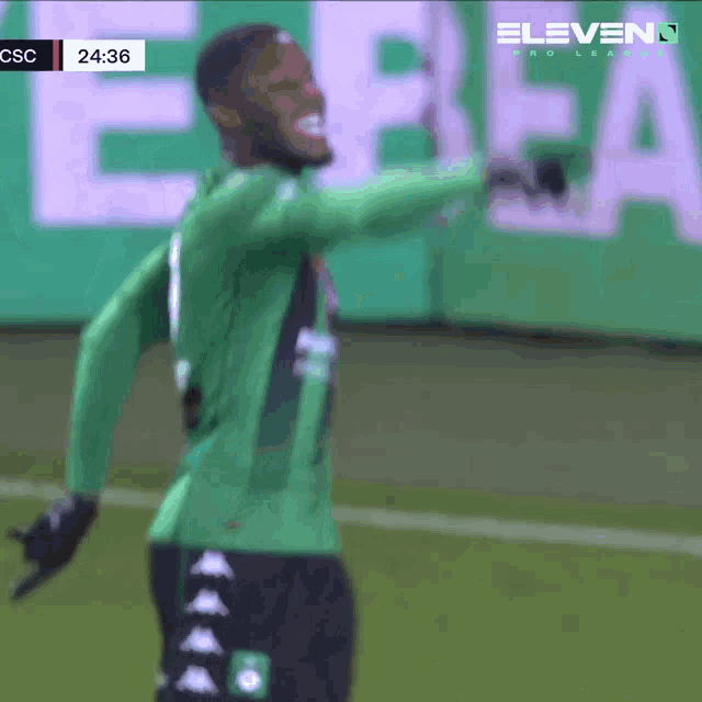 a soccer player in a green jersey stands on a field with eleven pro league in the background