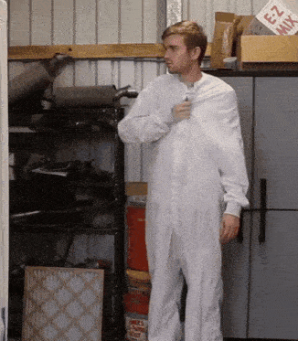 a man in a white jumpsuit is standing in a garage next to a box that says ez mix on it