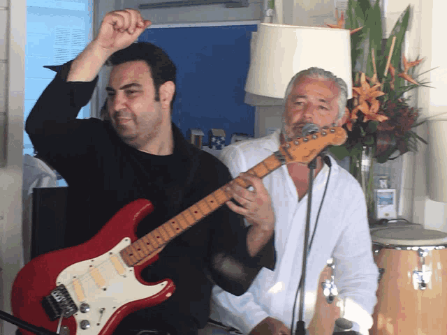 a man playing a red guitar with the letter g on the neck