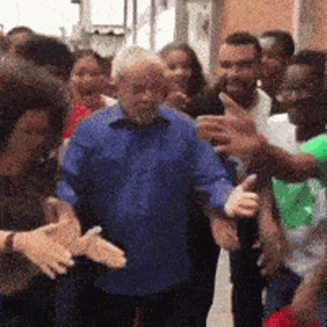 a man in a blue shirt is surrounded by a crowd