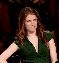 a woman in a green dress is sitting in a chair with her arms outstretched .