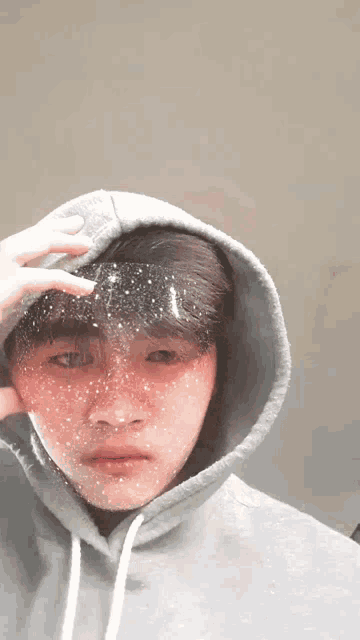 a young man wearing a hooded sweatshirt has a sticker on his face that looks like stars