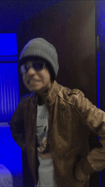a person wearing a beanie and sunglasses is standing in front of a door