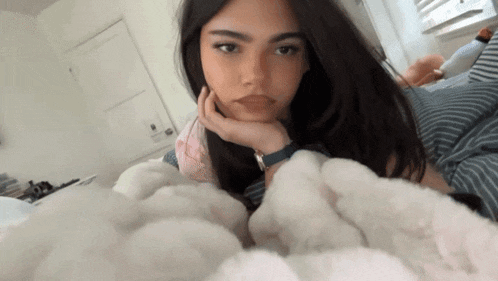 a woman laying on a bed with her head resting on her hand