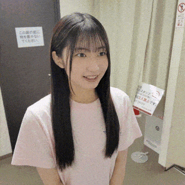 a girl in a pink shirt is smiling in front of a sign that says no smoking