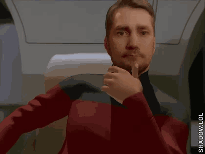 a man in a red jacket is giving the thumbs up