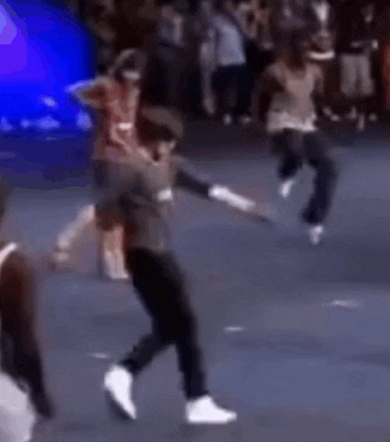 a group of people are dancing on a stage in front of a crowd of people .