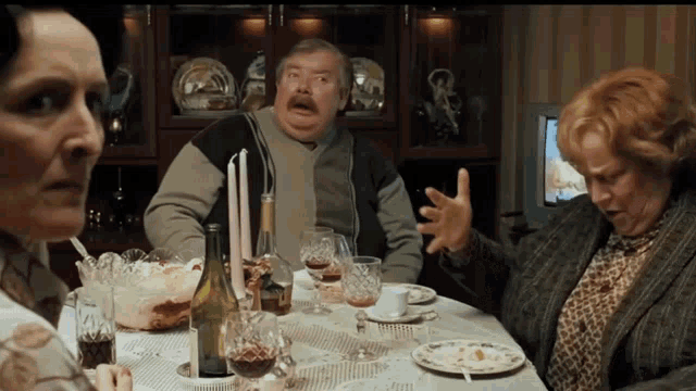 a group of people are sitting at a table with a bottle of wine