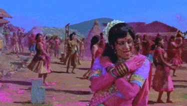a woman in a pink and blue dress stands in front of a crowd