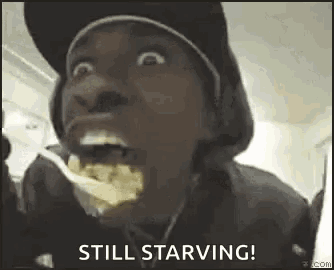 a man in a hat is eating food with a fork and making a funny face .