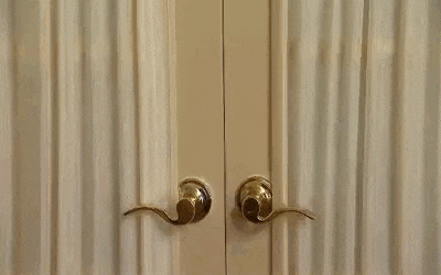 a person is standing in a room behind a door with a curtain .