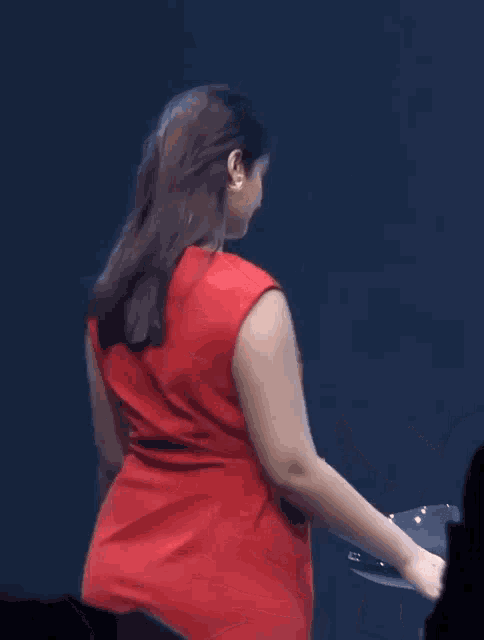 a woman in a red dress is standing in front of a crowd