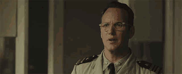 a man in a military uniform is wearing glasses