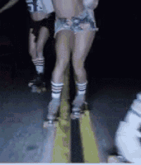 a woman wearing shorts and socks is rollerblading down a street