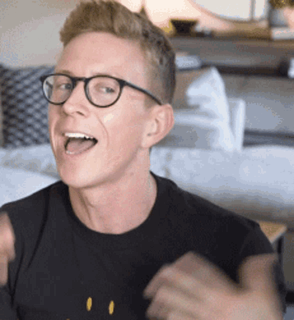 a man wearing glasses and a black shirt with a yellow smiley face on it