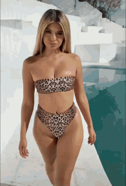 a woman in a leopard print bikini is walking along a sidewalk
