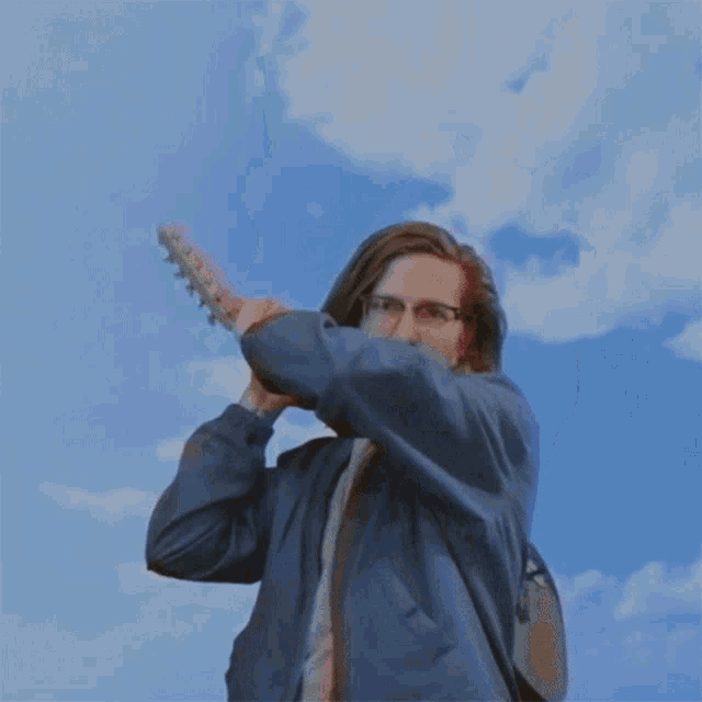 a man wearing glasses and a blue jacket is holding something in his hands