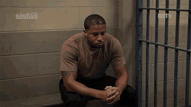 a man in a jail cell with sistas written on the wall