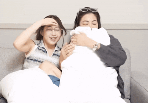 two women are sitting on a couch looking at a phone