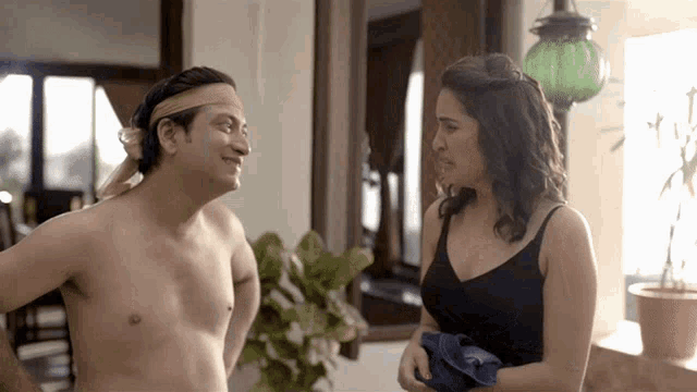 a shirtless man and a woman are standing next to each other in a room