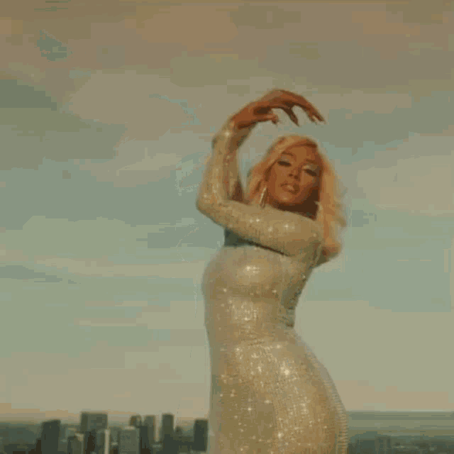 a woman in a white sequined dress is standing in front of a city skyline .