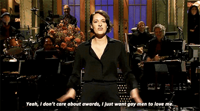 a woman in a black shirt stands in front of an orchestra and says yeah
