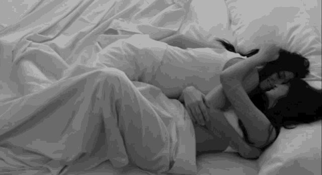 two women are hugging each other while laying in bed