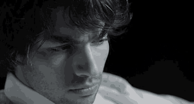 a close up of a man 's face with a white shirt around his neck