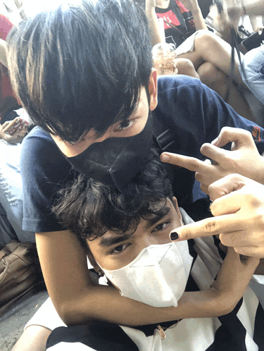 a man wearing a mask is laying on another man 's shoulder