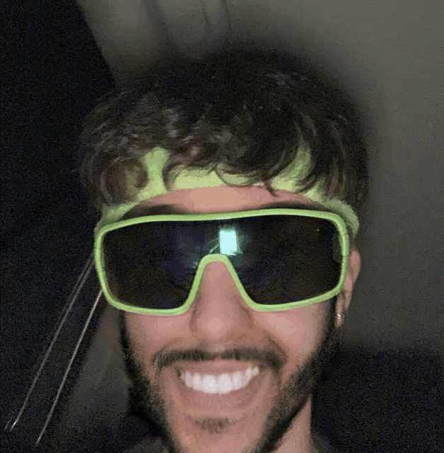 a man wearing sunglasses and a headband smiles for the camera