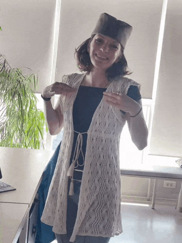 a woman wearing a hat and a white vest smiles