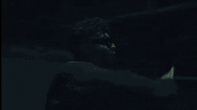a man wearing sunglasses and a choker is standing in a dark room