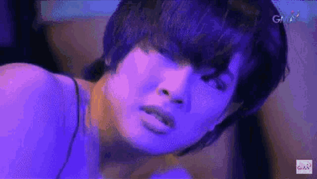 a close up of a person 's face with purple lights behind her .