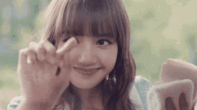 a close up of a woman making a peace sign with her hands .