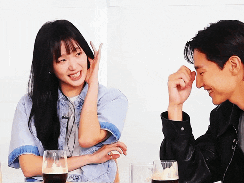a man and a woman are sitting at a table with glasses of beer in front of them