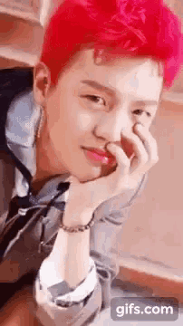 a young man with red hair is holding his nose .