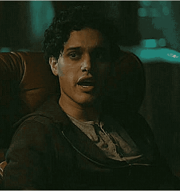 a man is sitting in a chair with his mouth open and looking at the camera .