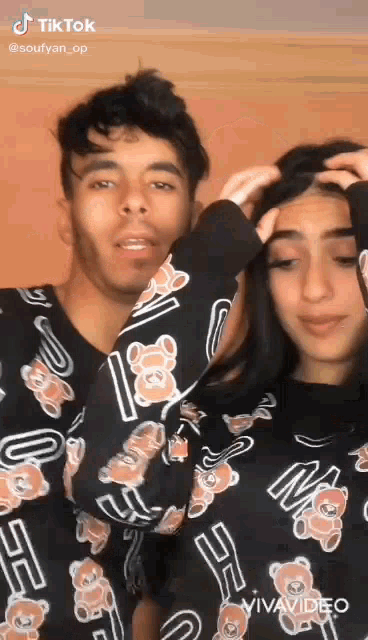 a man and a woman are standing next to each other wearing matching teddy bear sweaters .