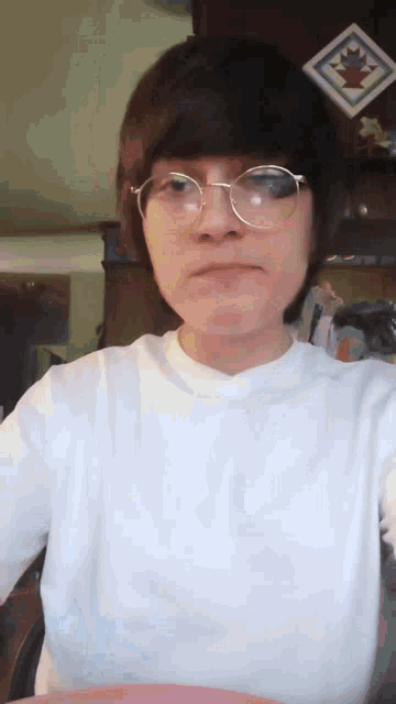 a person wearing glasses and a white shirt is looking at the camera .