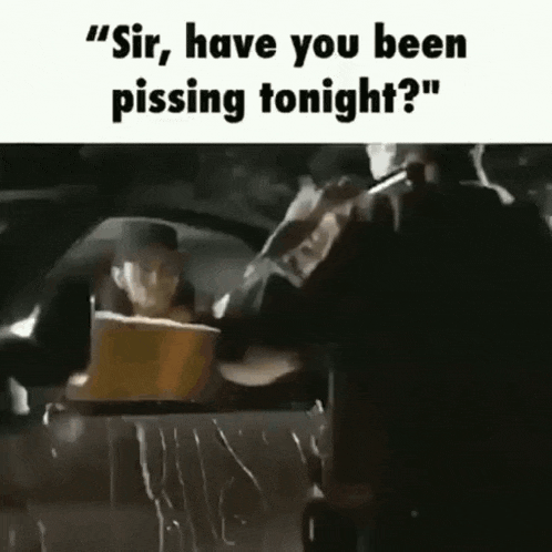 a man is sitting in a car talking to another man while another man stands behind him .