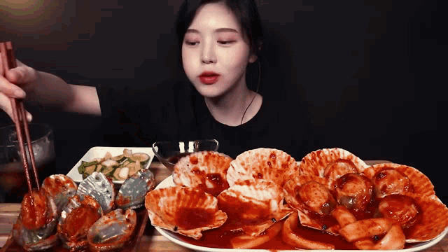 a woman is eating a plate of food with chopsticks .