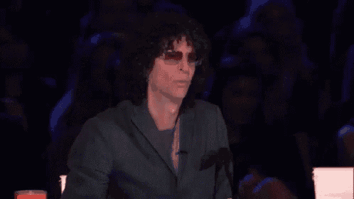 a man with curly hair is sitting in front of a microphone with his mouth open