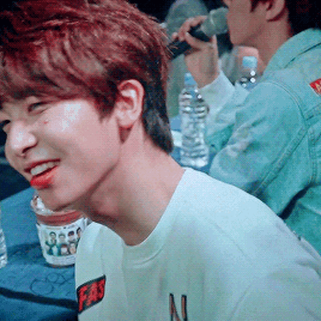 a young man with red hair is smiling while holding a microphone