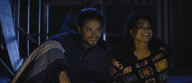 a man and a woman are sitting next to each other in the dark