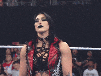 two female wrestlers are standing in a ring with a crowd behind them