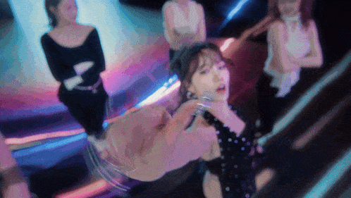 a woman in a black dress is dancing in front of a group of women