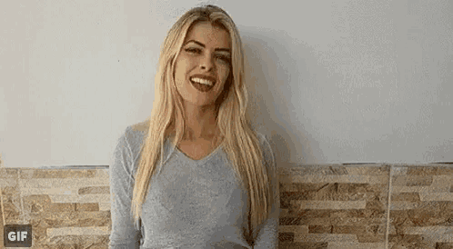 a woman is standing in front of a wall and smiling .