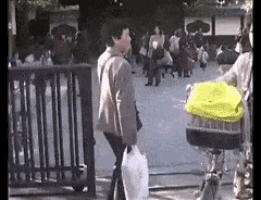a woman is walking down a street carrying a bag and a yellow jacket .