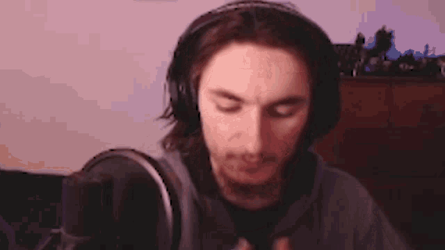 a man wearing headphones is sitting in front of a microphone in a room .